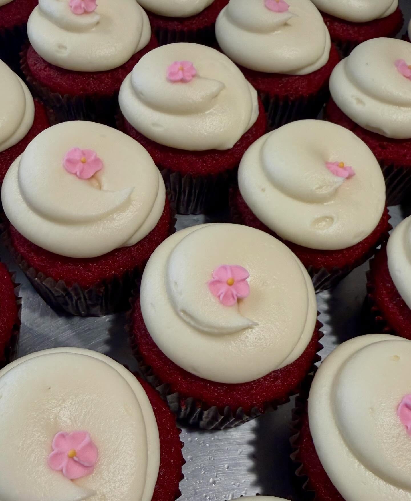 Tray of red velvet cupcakes with cream cheese frosting and pink sugar blooms